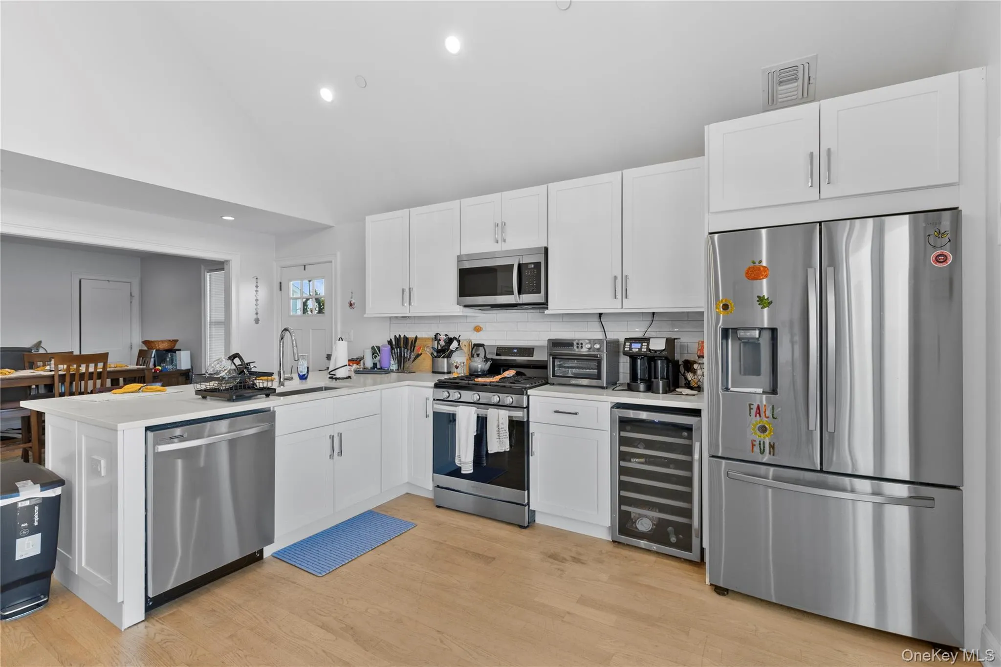 Kitchen featuring stainless steel appliances, white cabinetry, recessed lighting, a peninsula, and beverage cooler Kitchen featuring stainless steel appliances, white cabinetry, recessed lighting, a peninsula, and beverage cooler