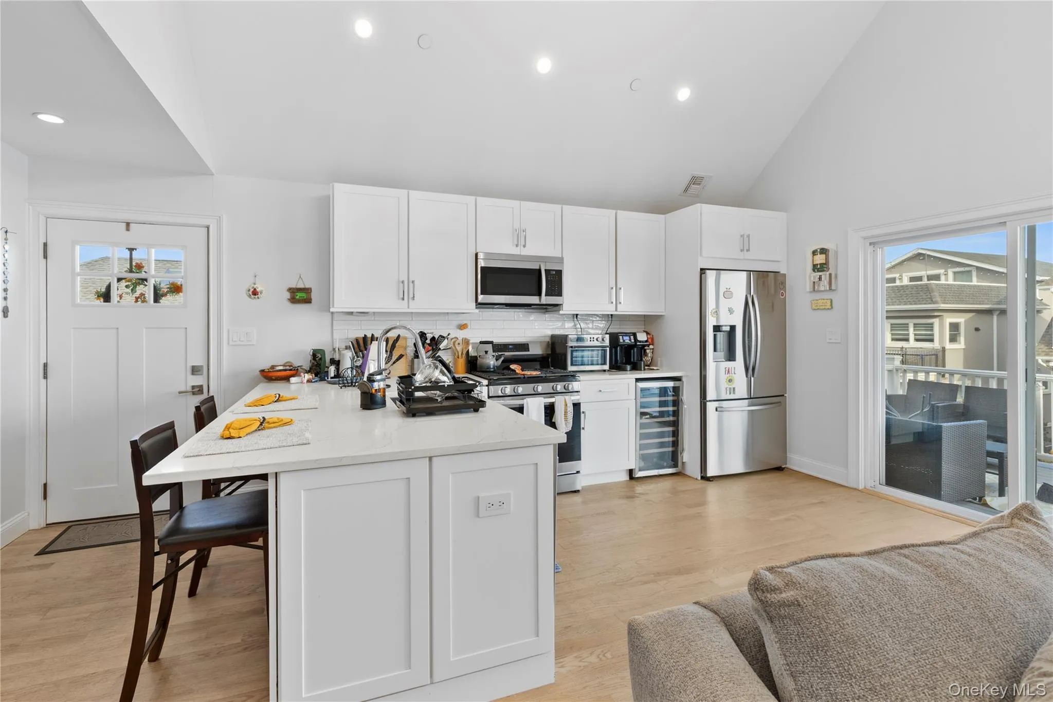 Kitchen with white cabinetry, backsplash, stainless steel appliances, light stone counters, and recessed lighting Kitchen with white cabinetry, backsplash, stainless steel appliances, light stone counters, and recessed lighting