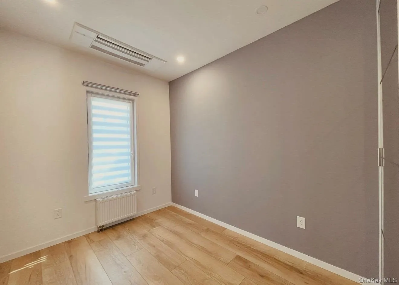 Empty room featuring light wood-style flooring and radiator Empty room featuring light wood-style flooring and radiator