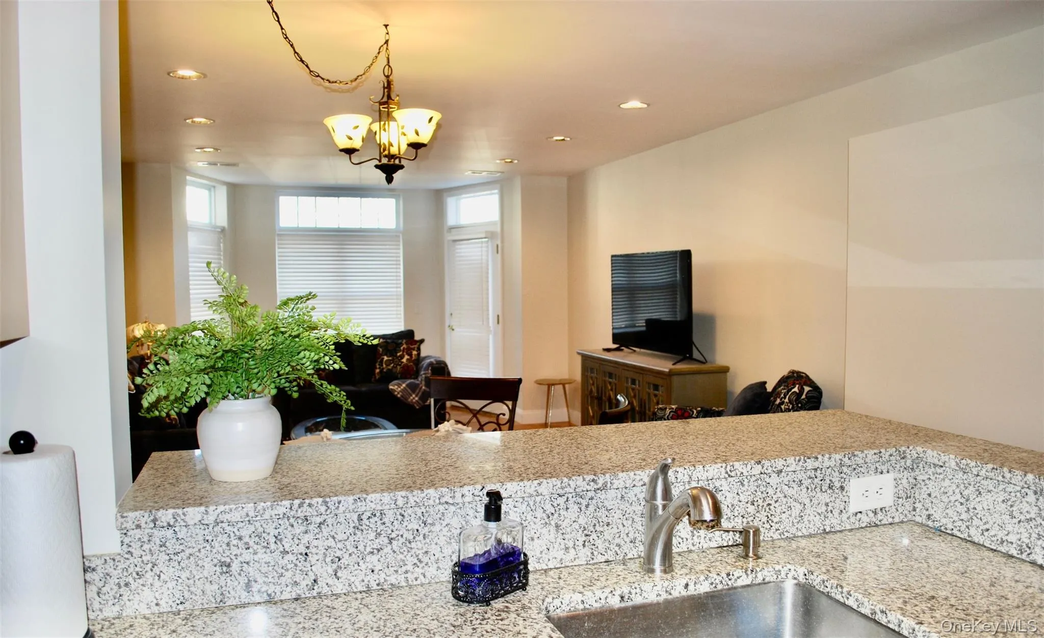 Kitchen featuring recessed lighting, light stone counters, hanging light fixtures, and a chandelier Kitchen featuring recessed lighting, light stone counters, hanging light fixtures, and a chandelier