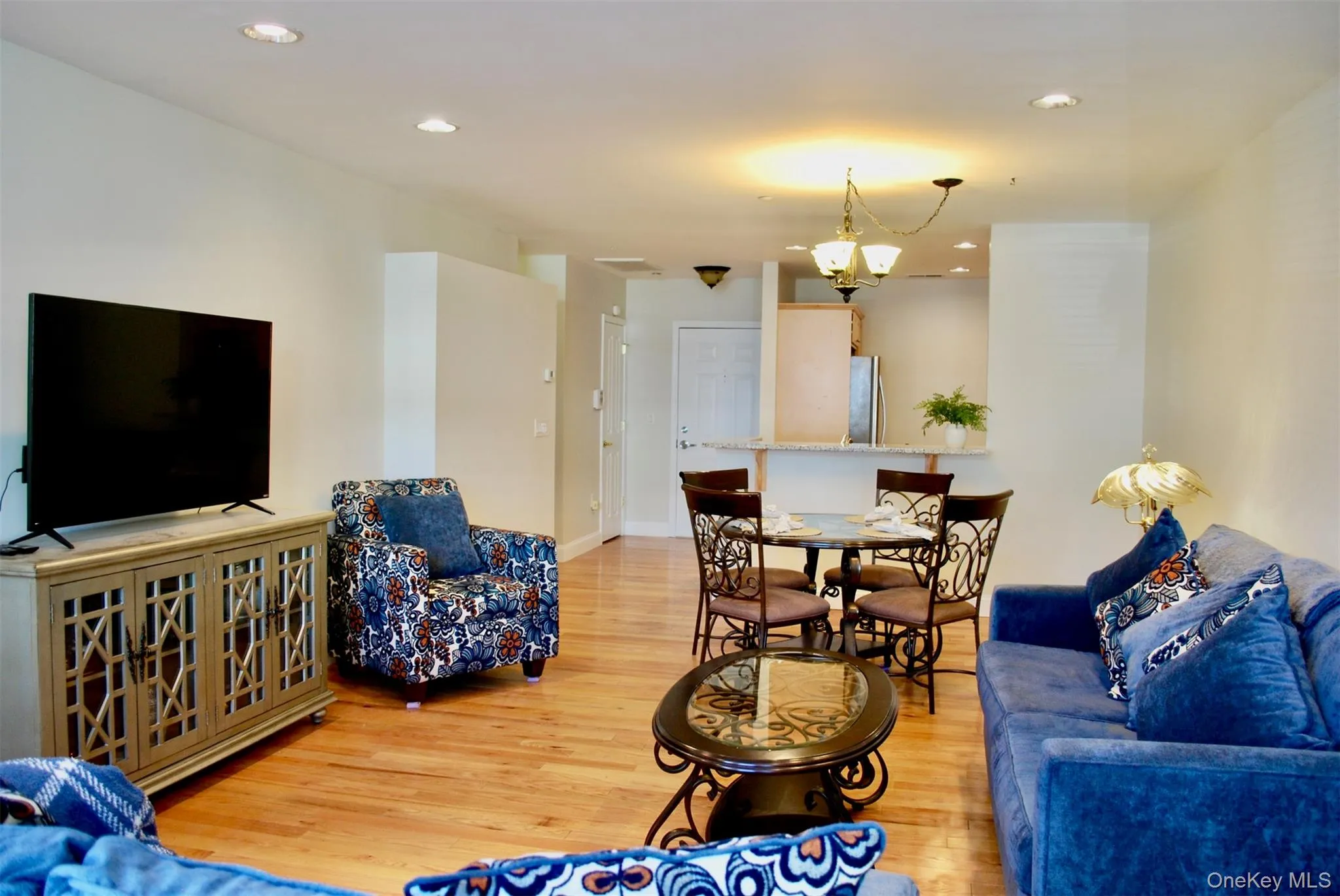 Living room with light wood-type flooring, recessed lighting, and a chandelier Living room with light wood-type flooring, recessed lighting, and a chandelier