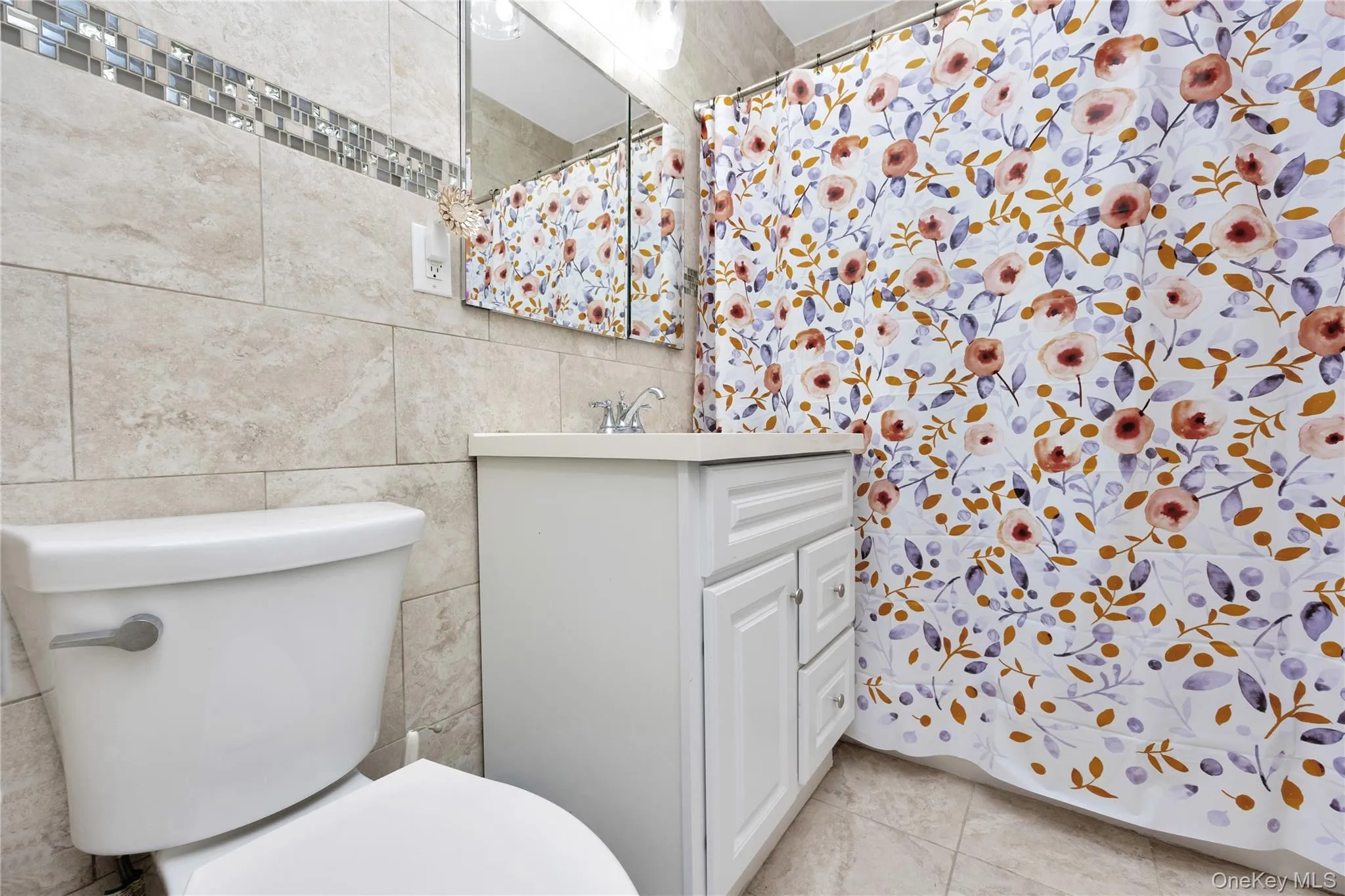 Full bathroom featuring vanity, a shower with curtain, tile walls, and light tile patterned floors Full bathroom featuring vanity, a shower with curtain, tile walls, and light tile patterned floors