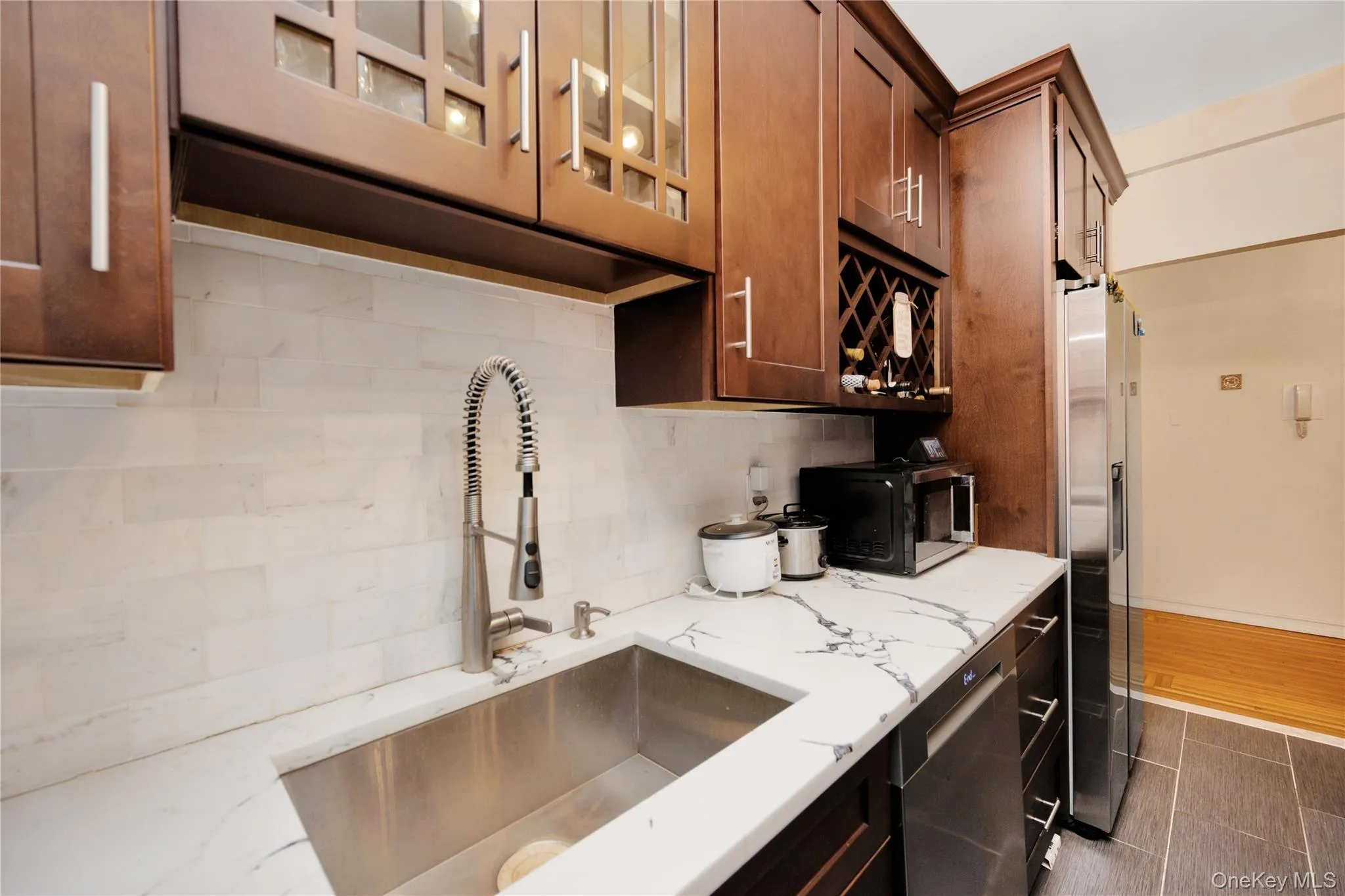 Kitchen with light stone counters, glass insert cabinets, decorative backsplash, and stainless steel appliances Kitchen with light stone counters, glass insert cabinets, decorative backsplash, and stainless steel appliances