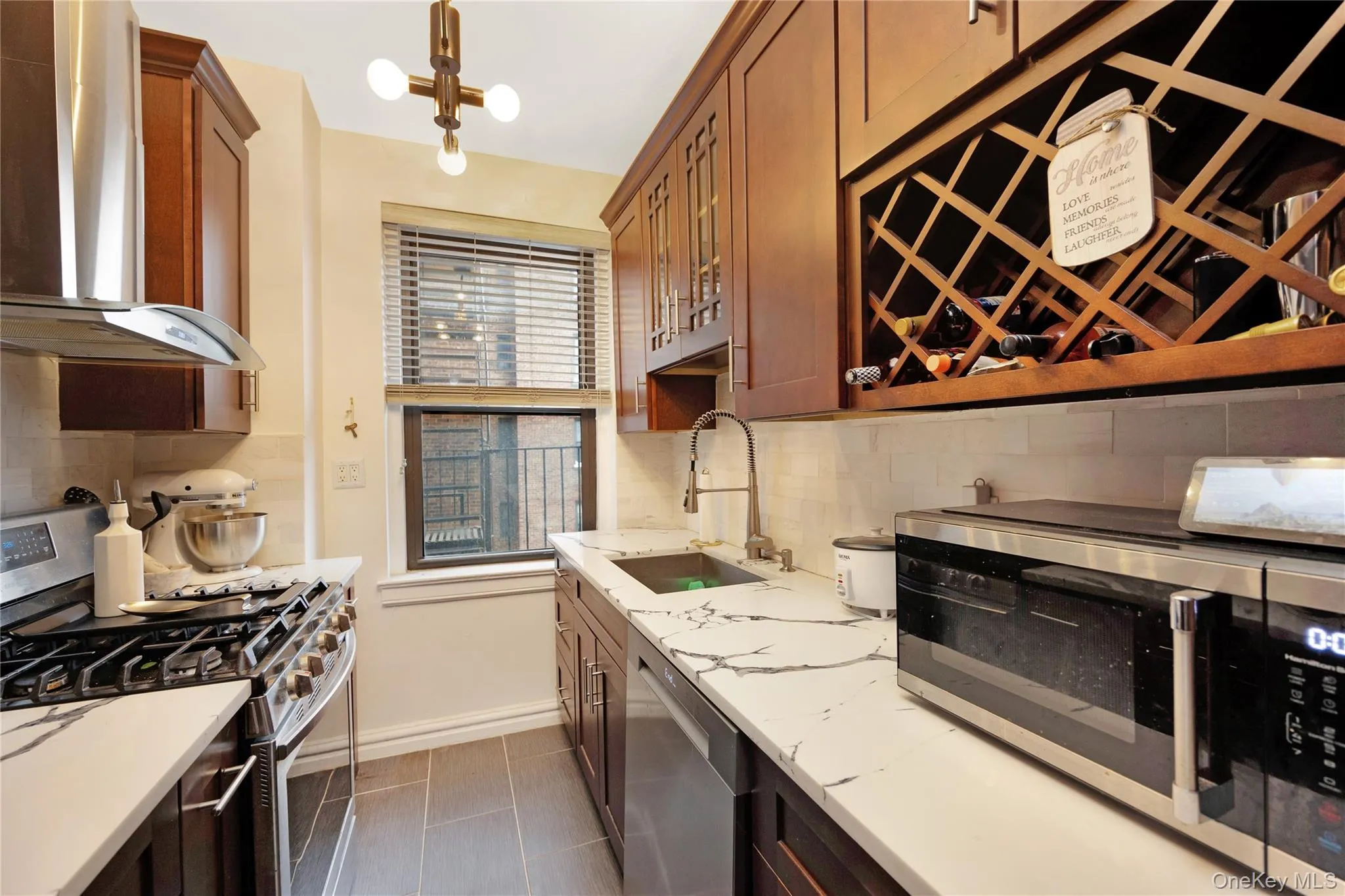 Kitchen with stainless steel appliances, exhaust hood, hanging light fixtures, dark tile patterned flooring, and glass insert cabinets Kitchen with stainless steel appliances, exhaust hood, hanging light fixtures, dark tile patterned flooring, and glass insert cabinets