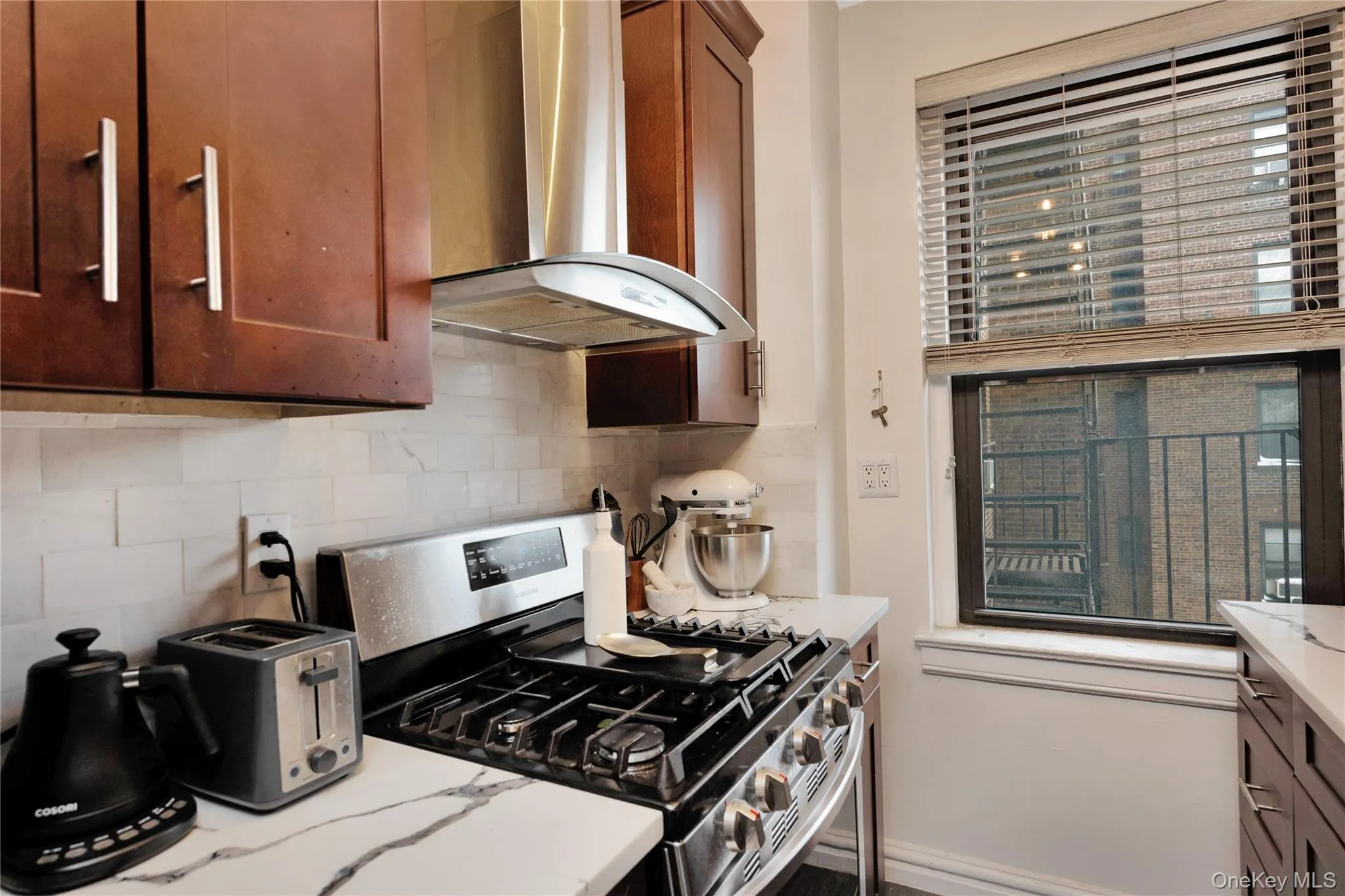 Kitchen with stainless steel gas range, extractor fan, decorative backsplash, and light stone counters Kitchen with stainless steel gas range, extractor fan, decorative backsplash, and light stone counters