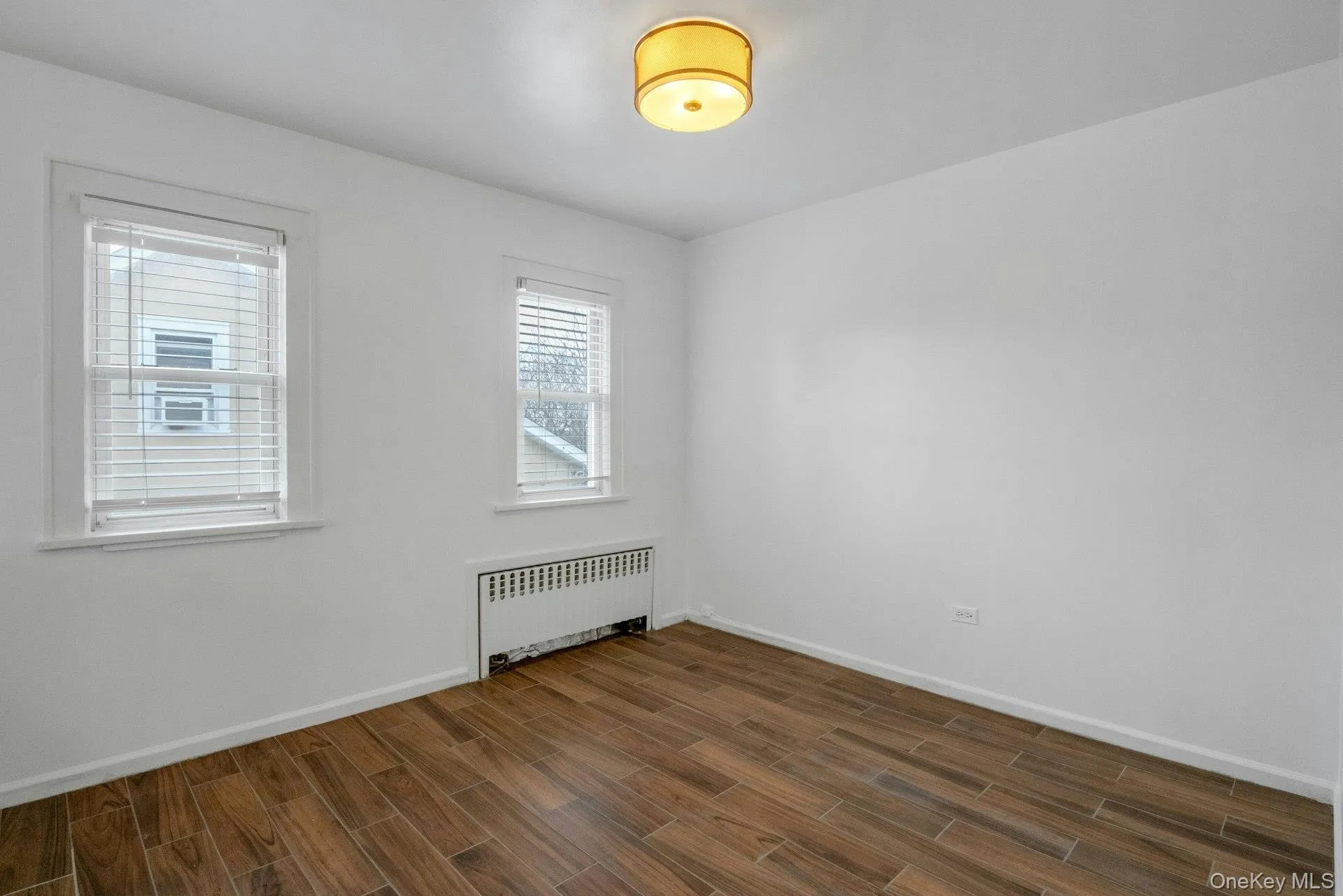 Unfurnished room with radiator heating unit and wood tiled floors Unfurnished room with radiator heating unit and wood tiled floors