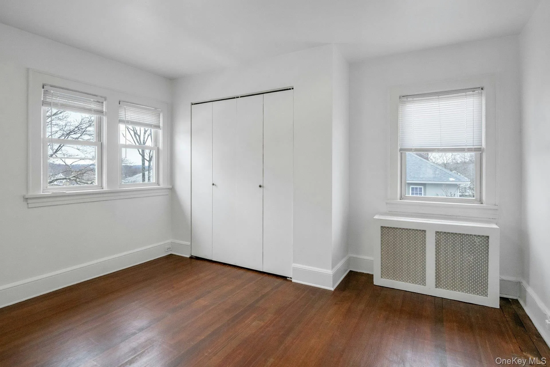 Unfurnished bedroom featuring radiator, dark wood-style floors, and a closet Unfurnished bedroom featuring radiator, dark wood-style floors, and a closet