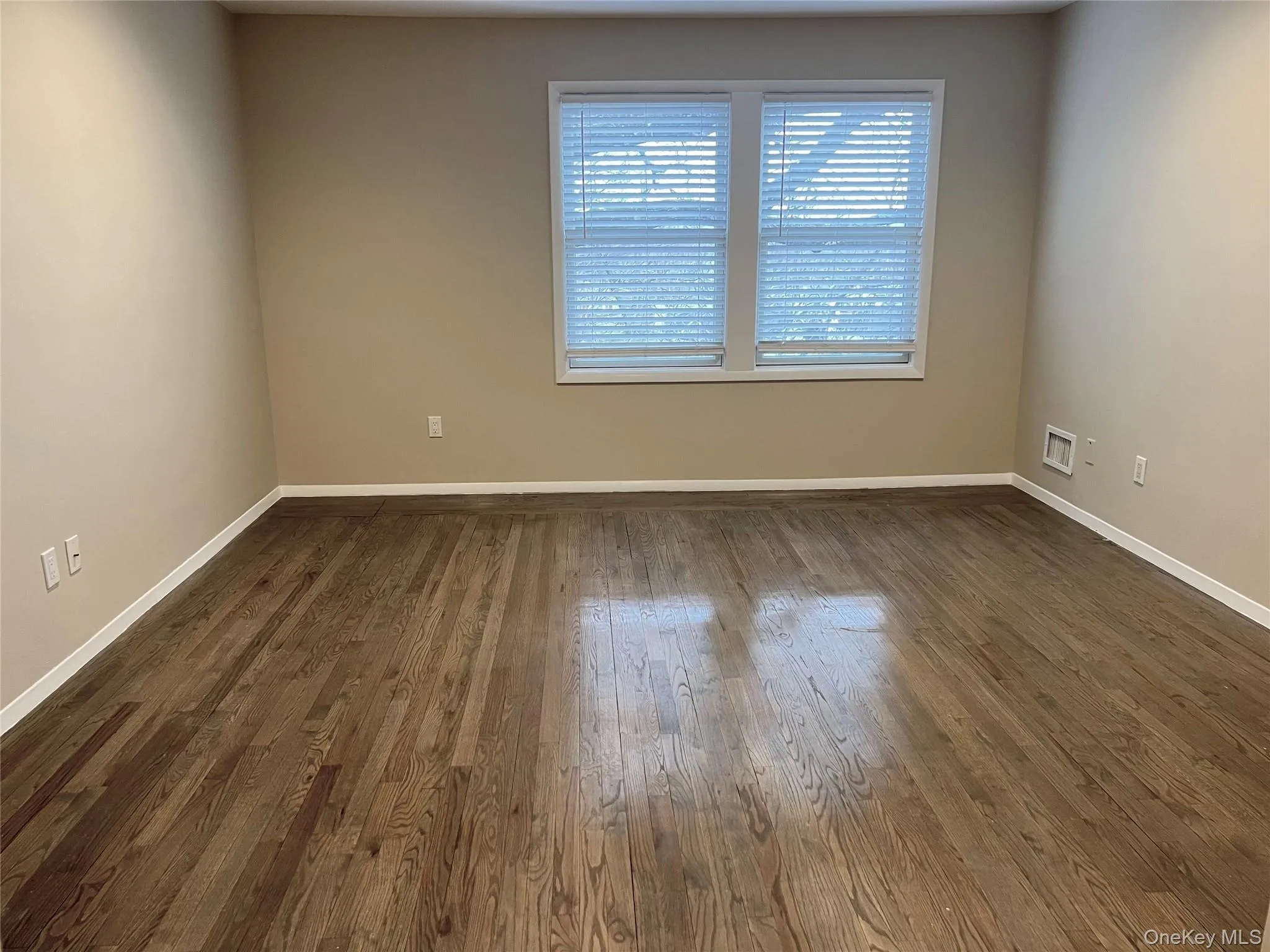 Spare room with baseboards and dark wood-style flooring Spare room with baseboards and dark wood-style flooring