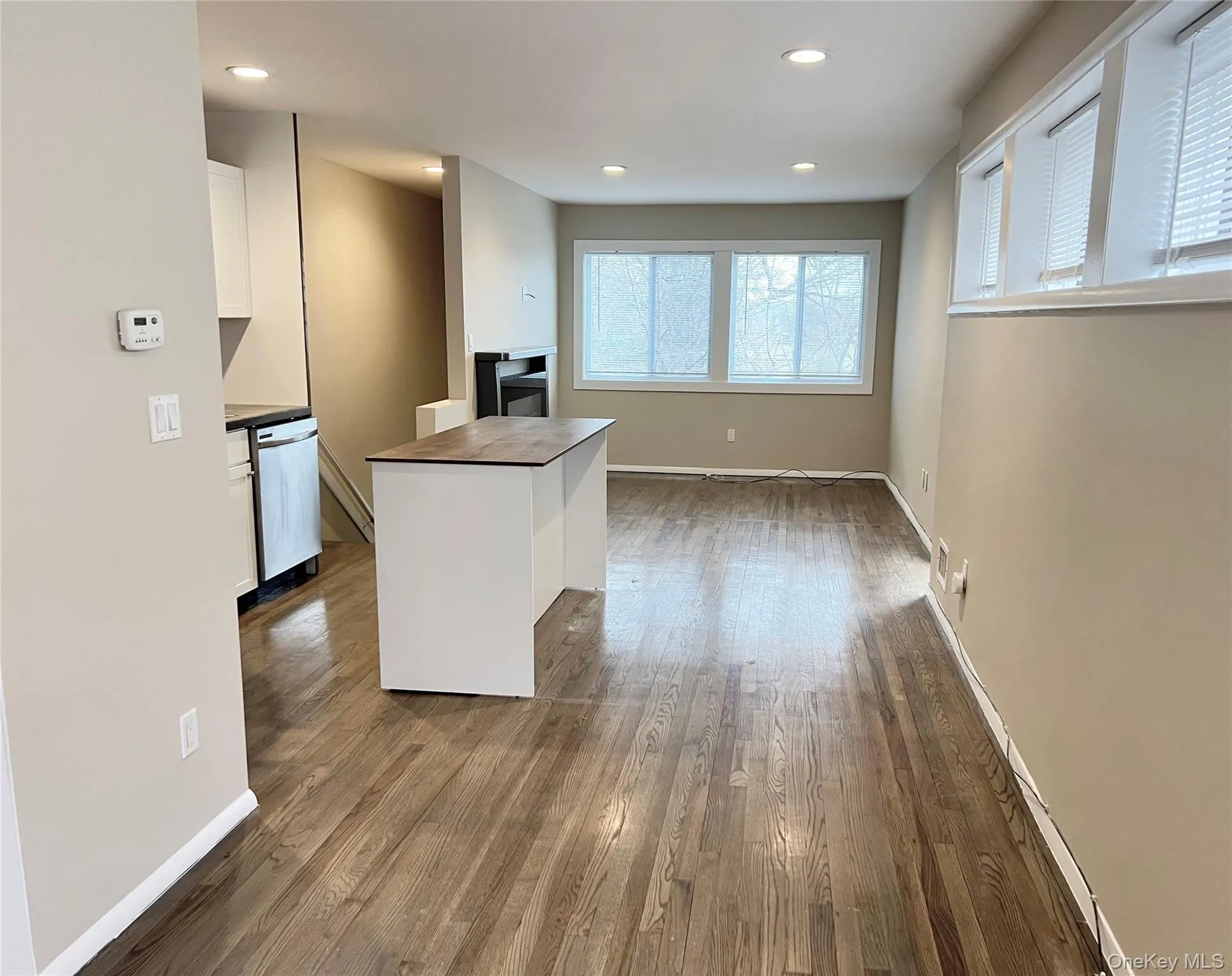 Kitchen with white cabinetry, recessed lighting, dark wood-style flooring, a kitchen island, and stainless steel dishwasher Kitchen with white cabinetry, recessed lighting, dark wood-style flooring, a kitchen island, and stainless steel dishwasher