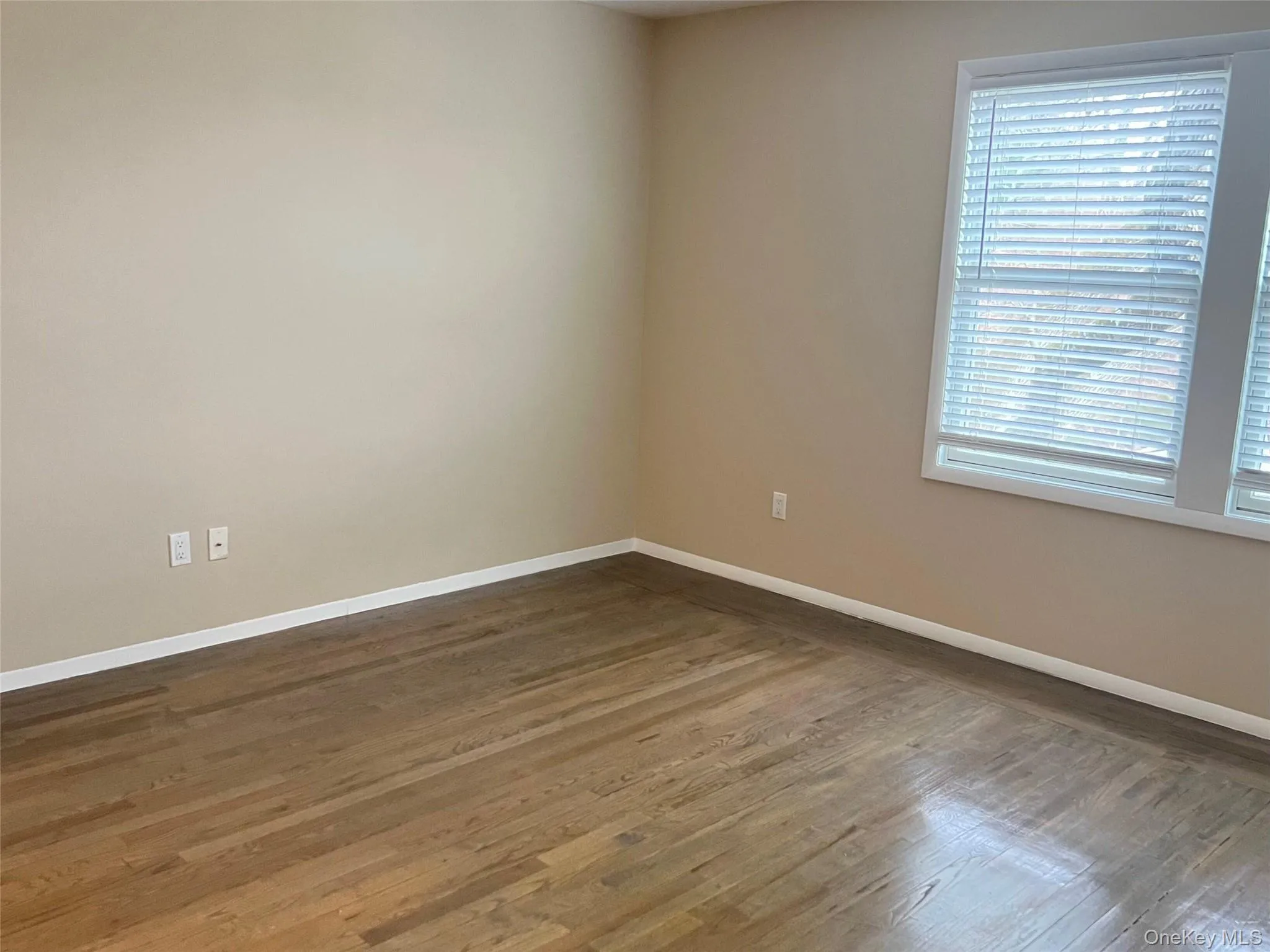 Spare room with baseboards and dark wood-type flooring Spare room with baseboards and dark wood-type flooring