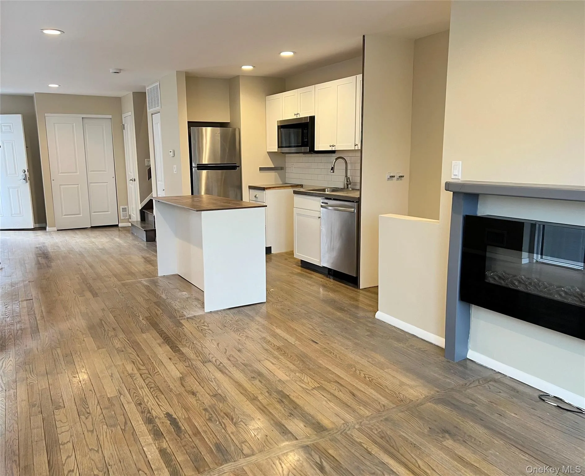 Kitchen with white cabinets, backsplash, appliances with stainless steel finishes, recessed lighting, and light wood-type flooring Kitchen with white cabinets, backsplash, appliances with stainless steel finishes, recessed lighting, and light wood-type flooring