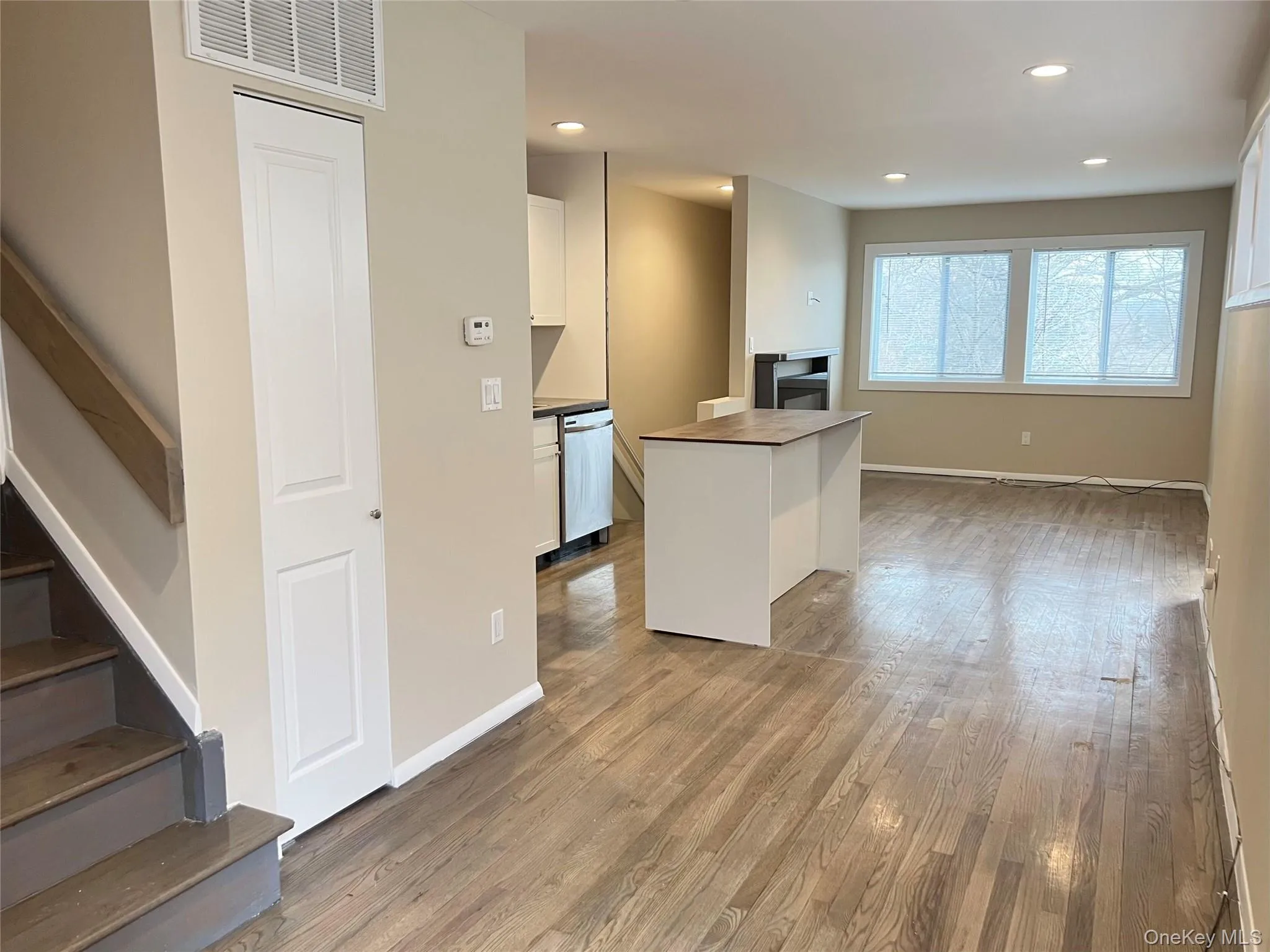 Kitchen with white cabinetry, light wood-style flooring, recessed lighting, stainless steel dishwasher, and open floor plan Kitchen with white cabinetry, light wood-style flooring, recessed lighting, stainless steel dishwasher, and open floor plan