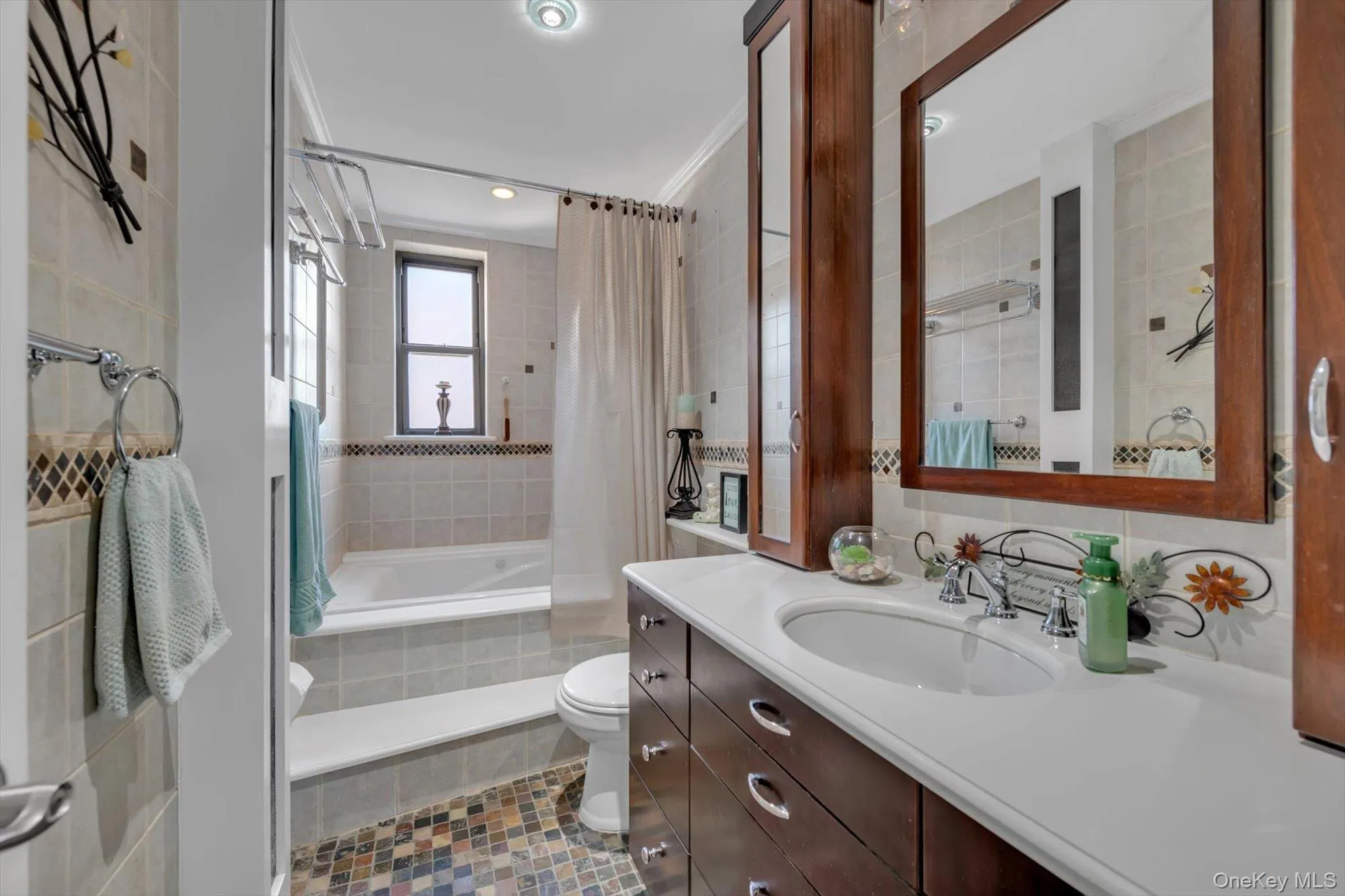 Bathroom featuring tile walls, vanity, tiled shower / bath, and crown molding Bathroom featuring tile walls, vanity, tiled shower / bath, and crown molding