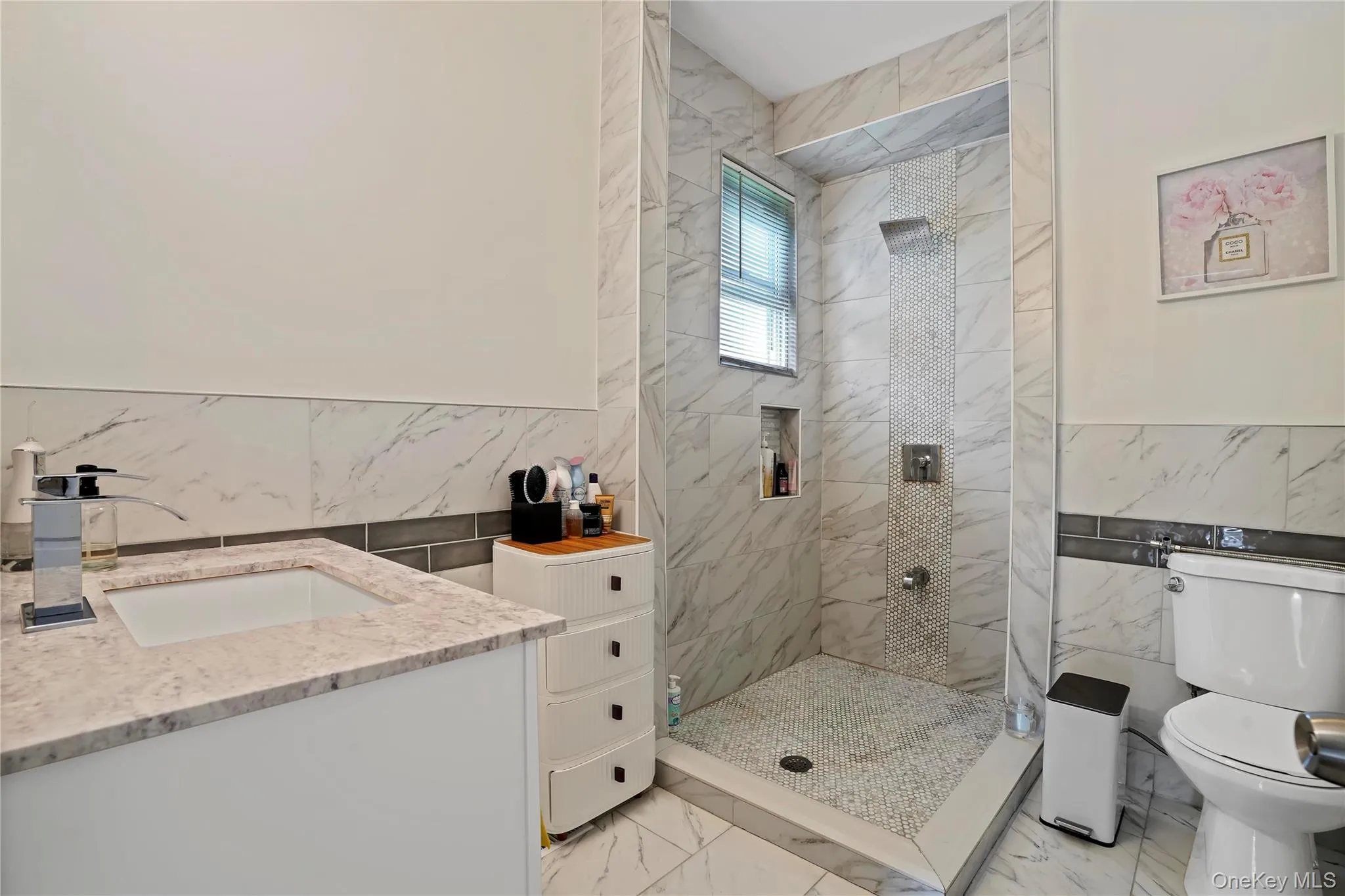 Bathroom with tile walls, wainscoting, light marble finish floors, vanity, and a stall shower Bathroom with tile walls, wainscoting, light marble finish floors, vanity, and a stall shower