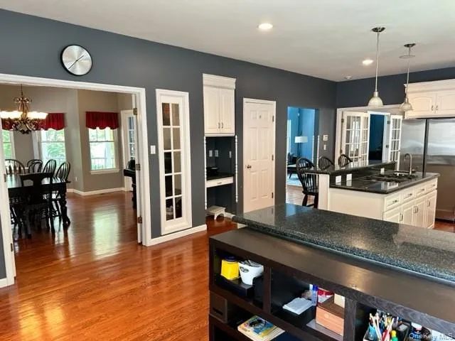 Kitchen with decorative light fixtures, white cabinets, freestanding refrigerator, and dark wood-style floors Kitchen with decorative light fixtures, white cabinets, freestanding refrigerator, and dark wood-style floors