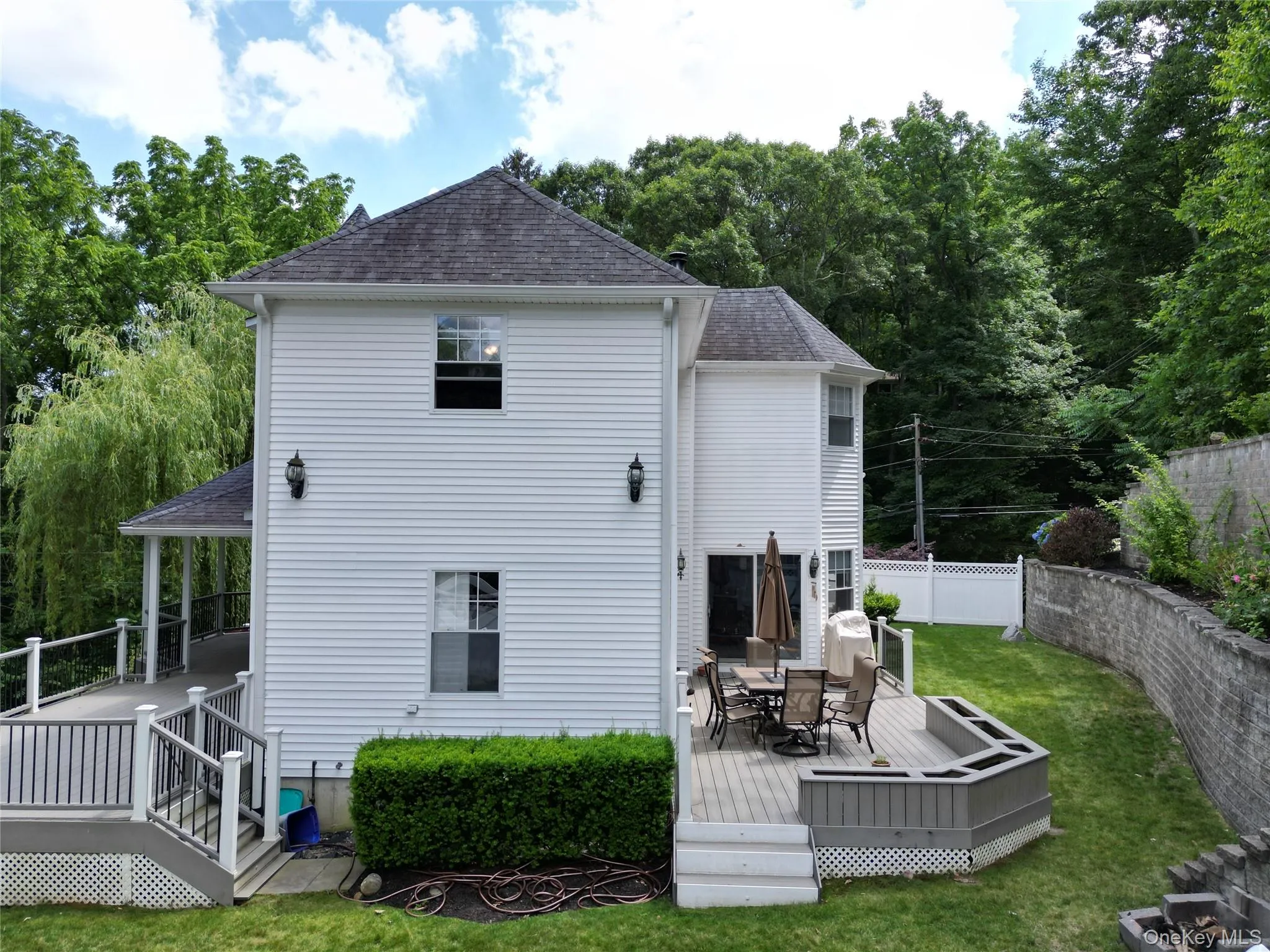 Rear view of house featuring a shingled roof, a wooden deck, and outdoor dining space Rear view of house featuring a shingled roof, a wooden deck, and outdoor dining space