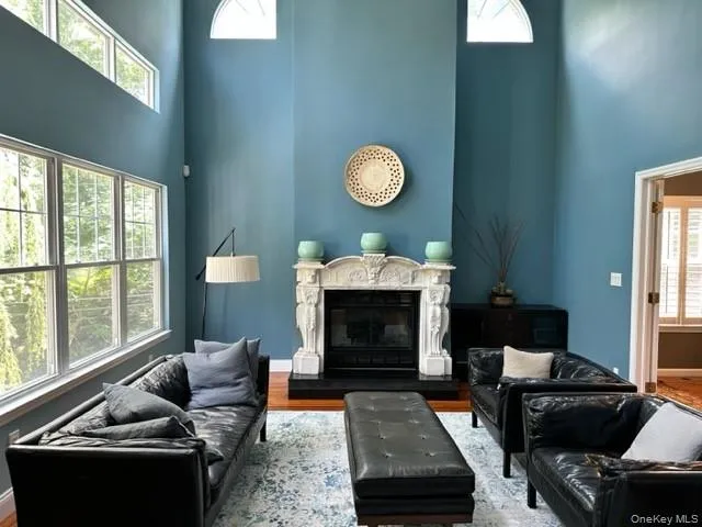 Living room with a high ceiling, a high end fireplace, and wood finished floors Living room with a high ceiling, a high end fireplace, and wood finished floors