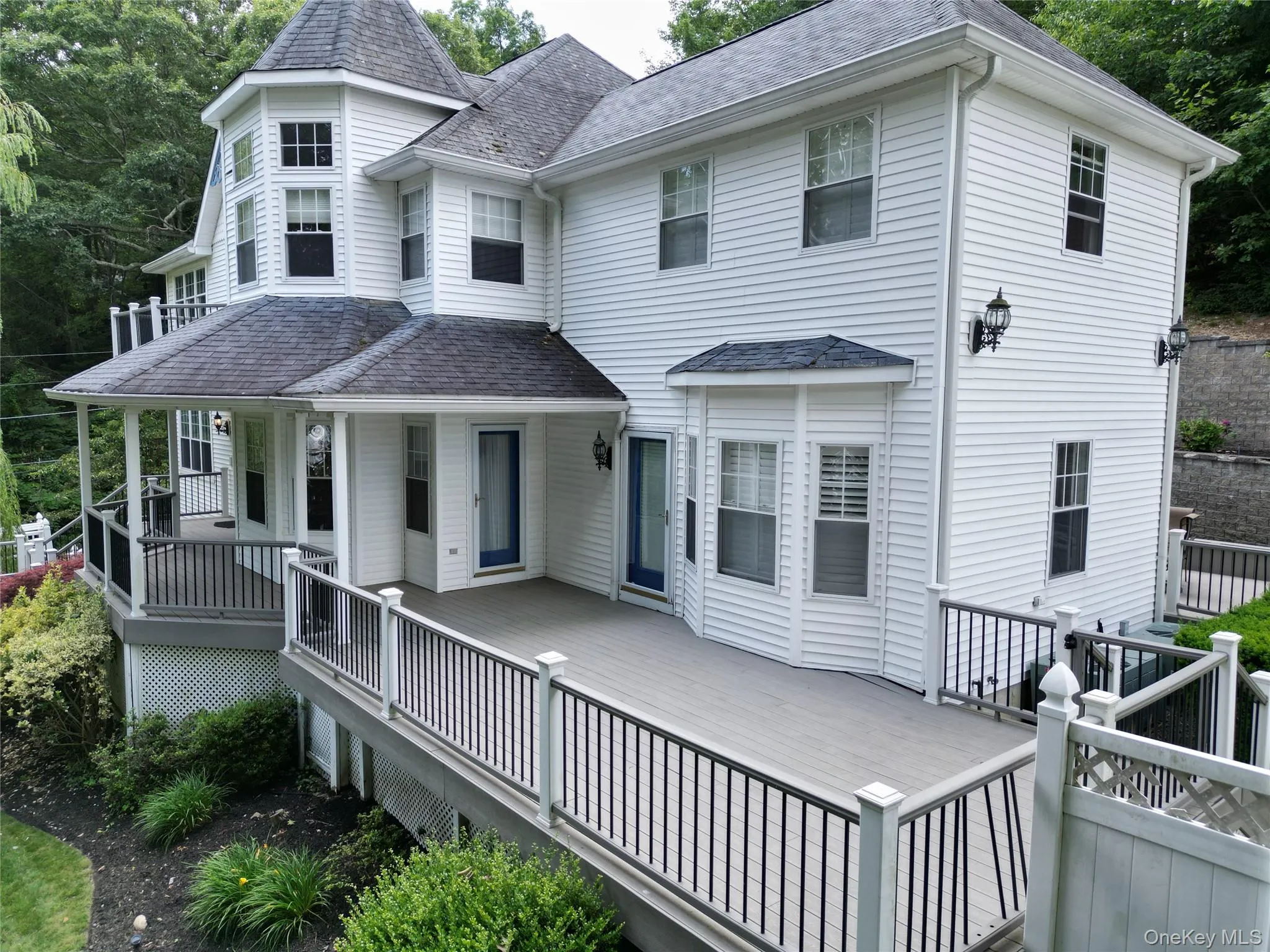 View of front of home with a deck and a shingled roof View of front of home with a deck and a shingled roof