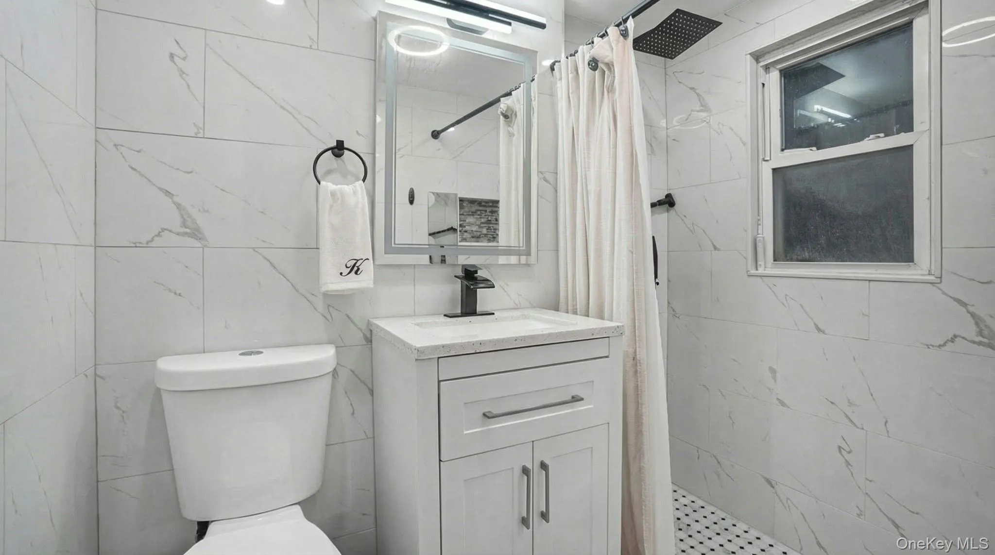 Bathroom with a marble finish shower, tile walls, and vanity Bathroom with a marble finish shower, tile walls, and vanity