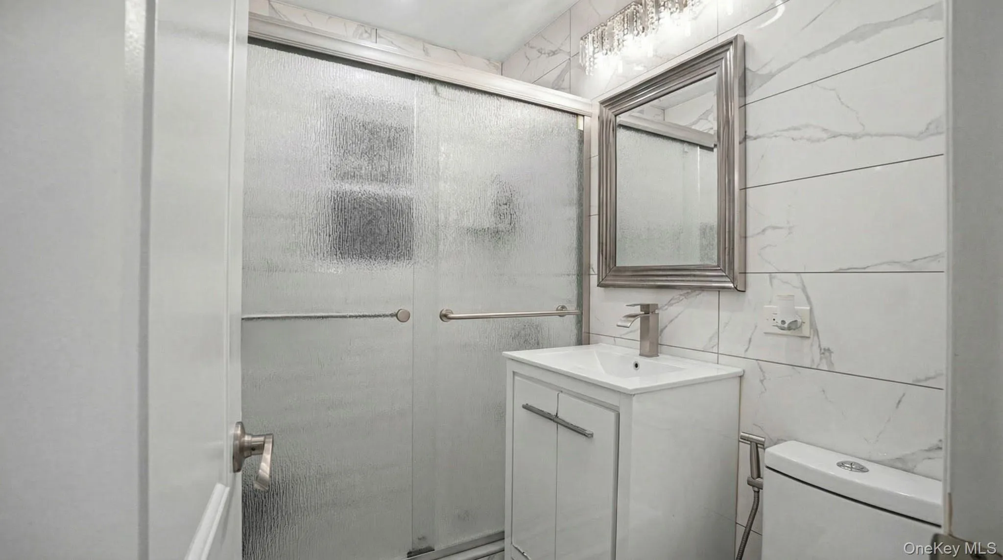 Bathroom featuring a stall shower, vanity, and tile walls Bathroom featuring a stall shower, vanity, and tile walls