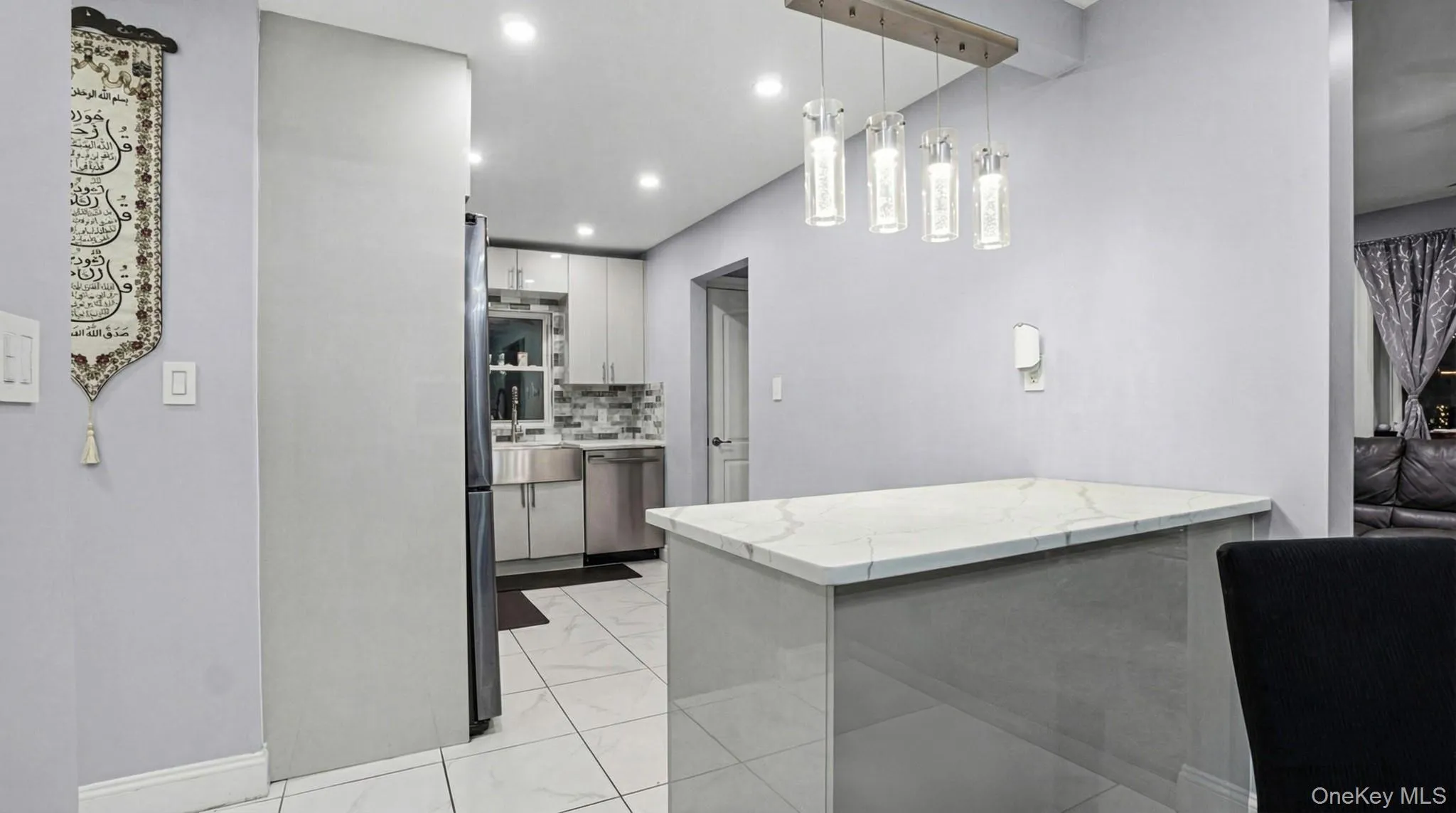 Kitchen with backsplash, decorative light fixtures, a peninsula, appliances with stainless steel finishes, and white cabinets Kitchen with backsplash, decorative light fixtures, a peninsula, appliances with stainless steel finishes, and white cabinets