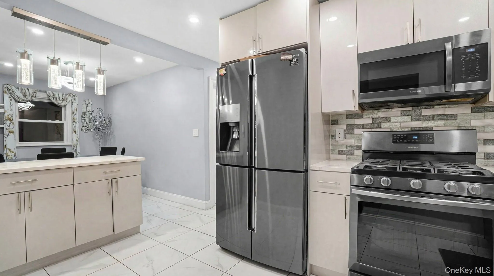 Kitchen featuring stainless steel appliances, decorative light fixtures, backsplash, recessed lighting, and light marble finish floors Kitchen featuring stainless steel appliances, decorative light fixtures, backsplash, recessed lighting, and light marble finish floors