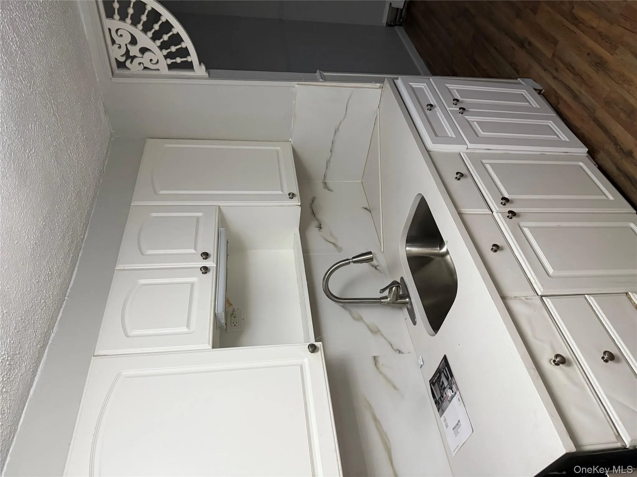 Kitchen featuring white cabinets, a textured ceiling, dark wood-style floors, light stone countertops, and a baseboard radiator Kitchen featuring white cabinets, a textured ceiling, dark wood-style floors, light stone countertops, and a baseboard radiator