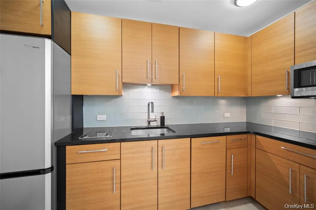 Kitchen with freestanding refrigerator, tasteful backsplash, and brown cabinetry Kitchen with freestanding refrigerator, tasteful backsplash, and brown cabinetry