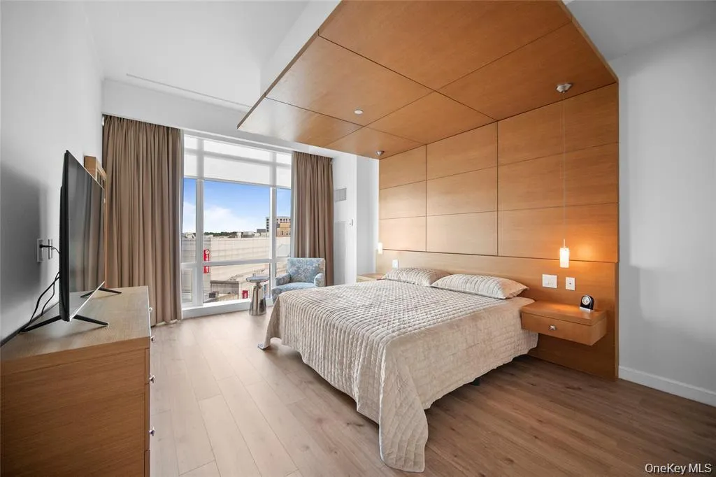 Bedroom with a wall of windows and light wood-type flooring Bedroom with a wall of windows and light wood-type flooring