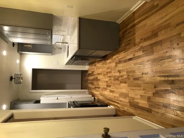 Kitchen with gray cabinetry, light stone counters, backsplash, recessed lighting, and light wood finished floors Kitchen with gray cabinetry, light stone counters, backsplash, recessed lighting, and light wood finished floors