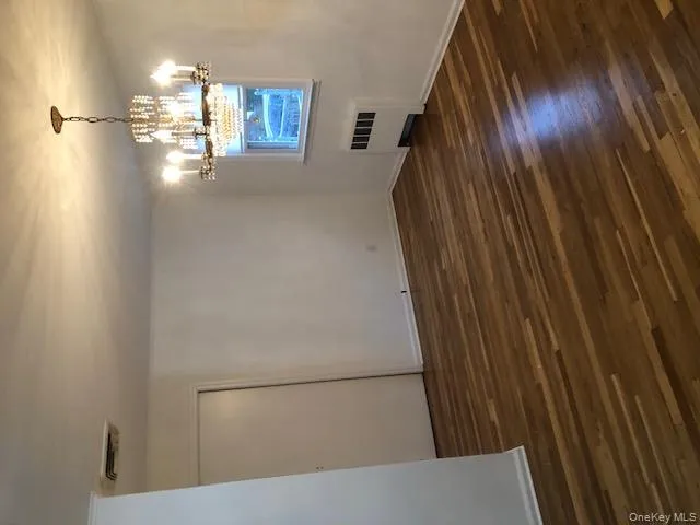 Unfurnished dining area featuring radiator, dark wood-style flooring, and a chandelier Unfurnished dining area featuring radiator, dark wood-style flooring, and a chandelier