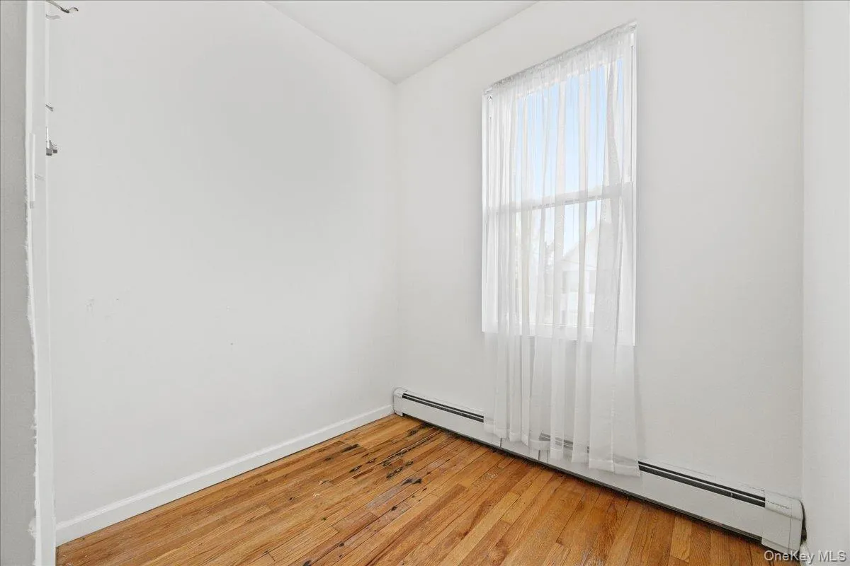 Spare room featuring a baseboard radiator, light wood-type flooring, and vaulted ceiling Spare room featuring a baseboard radiator, light wood-type flooring, and vaulted ceiling