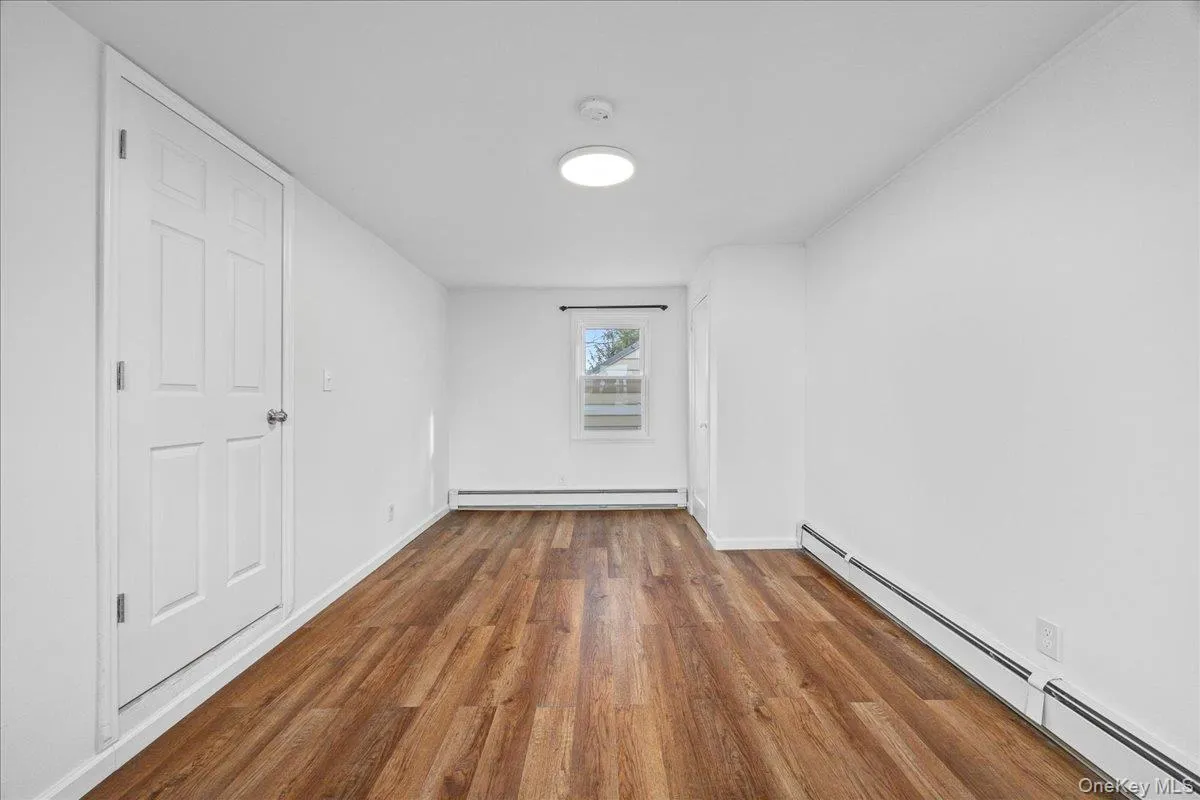 Unfurnished bedroom featuring a baseboard radiator, wood finished floors, and baseboard heating Unfurnished bedroom featuring a baseboard radiator, wood finished floors, and baseboard heating