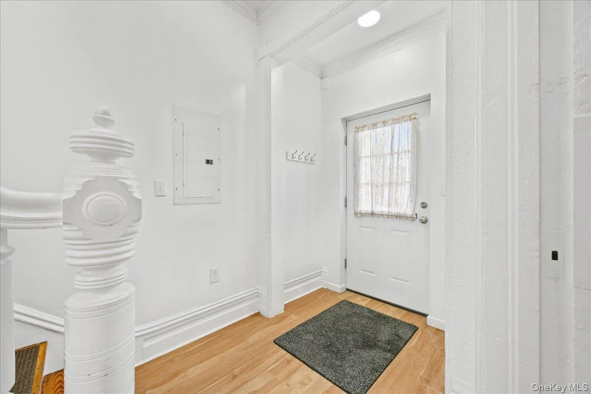 Doorway featuring electric panel, wood finished floors, and ornamental molding Doorway featuring electric panel, wood finished floors, and ornamental molding