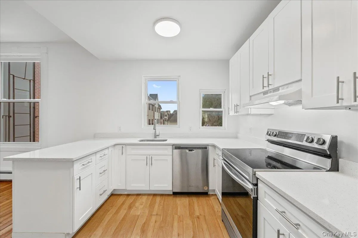 Kitchen with stainless steel appliances, white cabinetry, light wood-style flooring, and a peninsula Kitchen with stainless steel appliances, white cabinetry, light wood-style flooring, and a peninsula