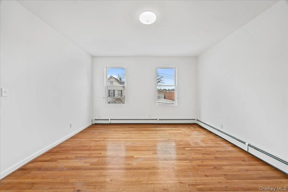 Unfurnished room featuring light wood finished floors and a baseboard radiator Unfurnished room featuring light wood finished floors and a baseboard radiator
