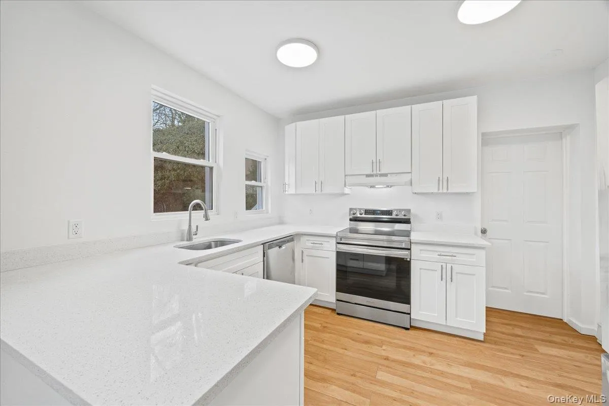 Kitchen featuring appliances with stainless steel finishes, white cabinets, light wood-style flooring, and light stone counters Kitchen featuring appliances with stainless steel finishes, white cabinets, light wood-style flooring, and light stone counters