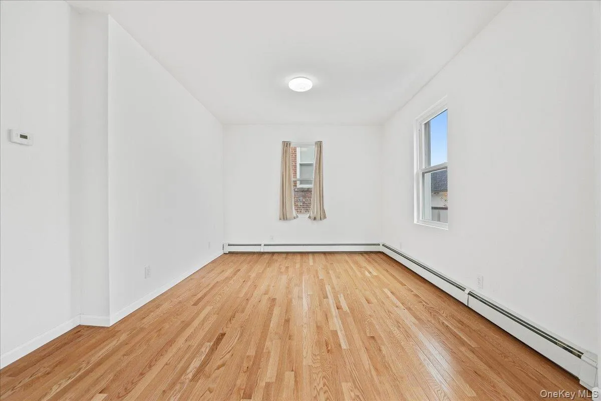 Spare room with a baseboard heating unit and light wood-style floors Spare room with a baseboard heating unit and light wood-style floors