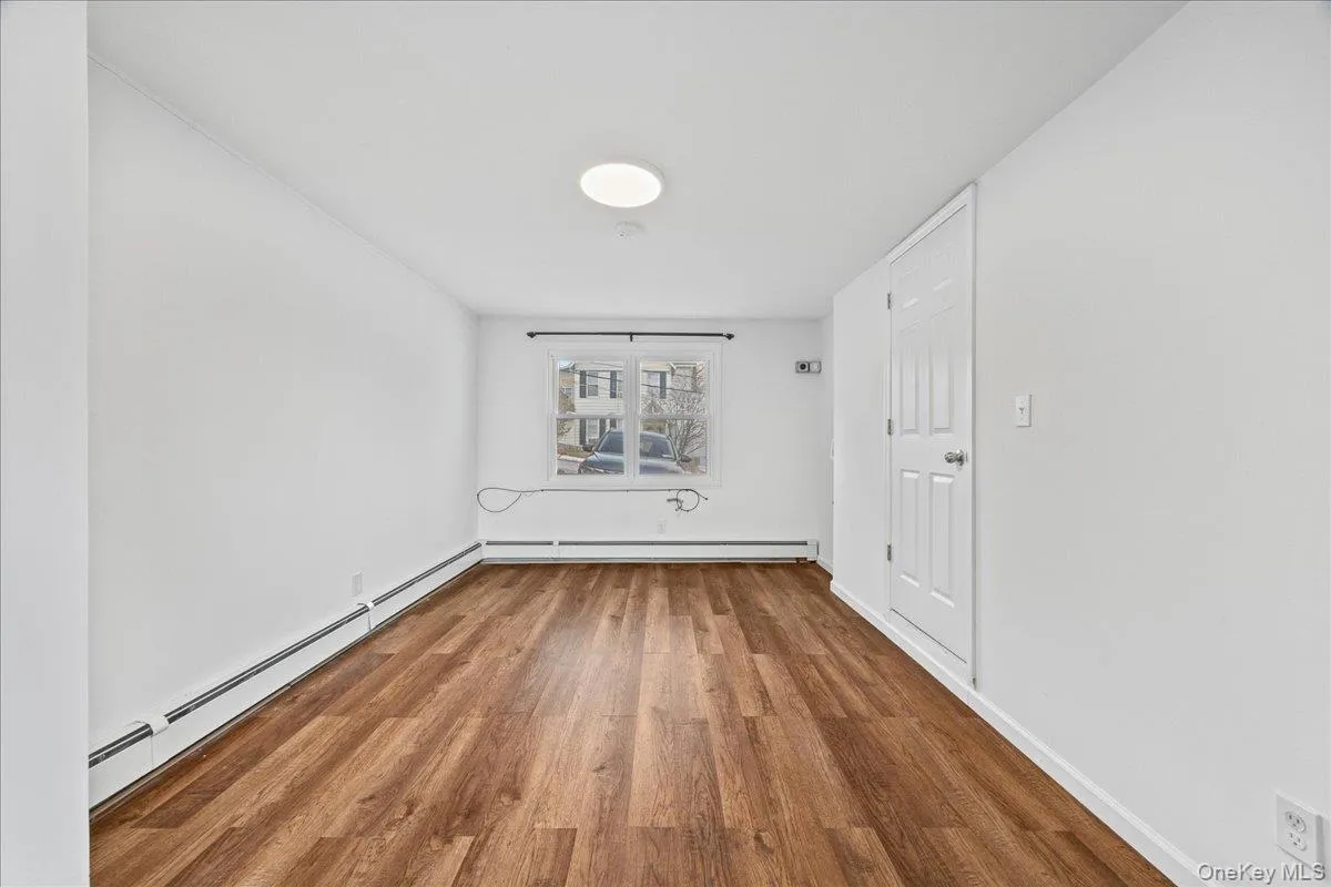 Spare room featuring wood finished floors and a baseboard heating unit Spare room featuring wood finished floors and a baseboard heating unit