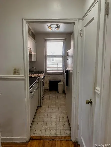Kitchen featuring gas range gas stove, white cabinets, light floors, and under cabinet range hood Kitchen featuring gas range gas stove, white cabinets, light floors, and under cabinet range hood