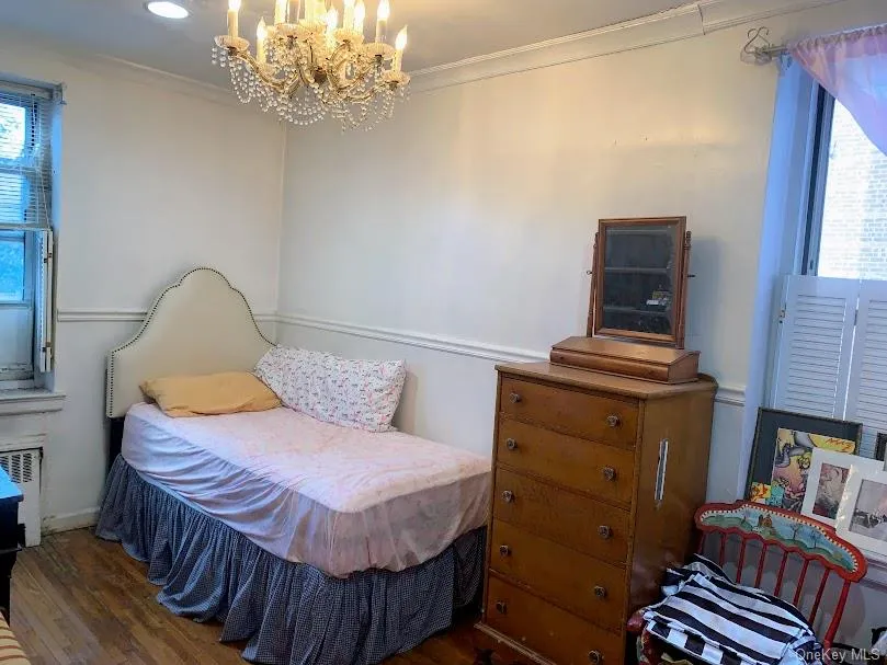 2nd Bedroom featuring multiple windows, radiator, crown molding, a chandelier, and wood finished floors 2nd Bedroom featuring multiple windows, radiator, crown molding, a chandelier, and wood finished floors