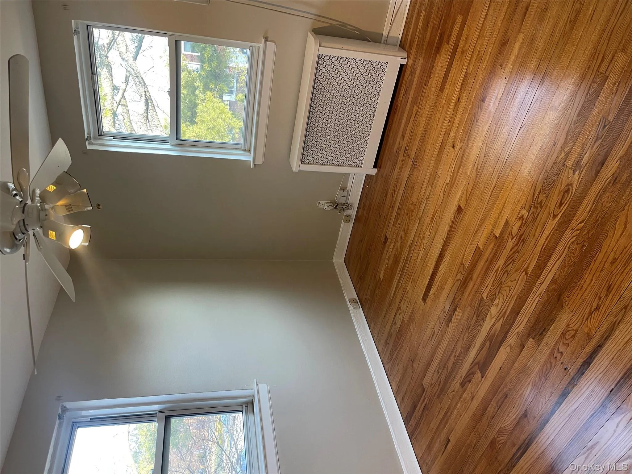 Spare room featuring radiator heating unit, light wood-style flooring, a ceiling fan, and healthy amount of natural light Spare room featuring radiator heating unit, light wood-style flooring, a ceiling fan, and healthy amount of natural light