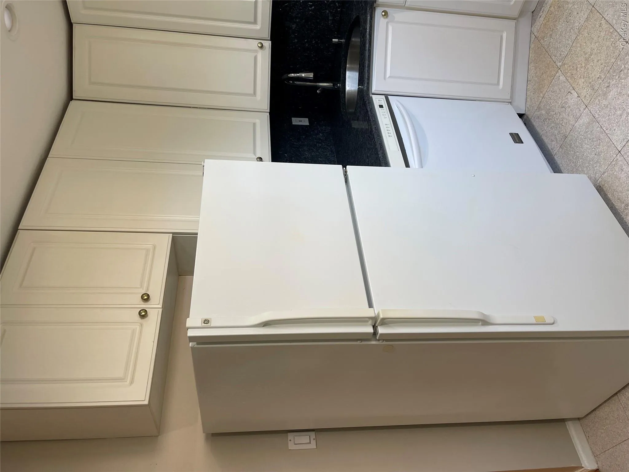 Kitchen with white appliances, white cabinetry, dark speckled floor, dark stone countertops, and tasteful backsplash Kitchen with white appliances, white cabinetry, dark speckled floor, dark stone countertops, and tasteful backsplash