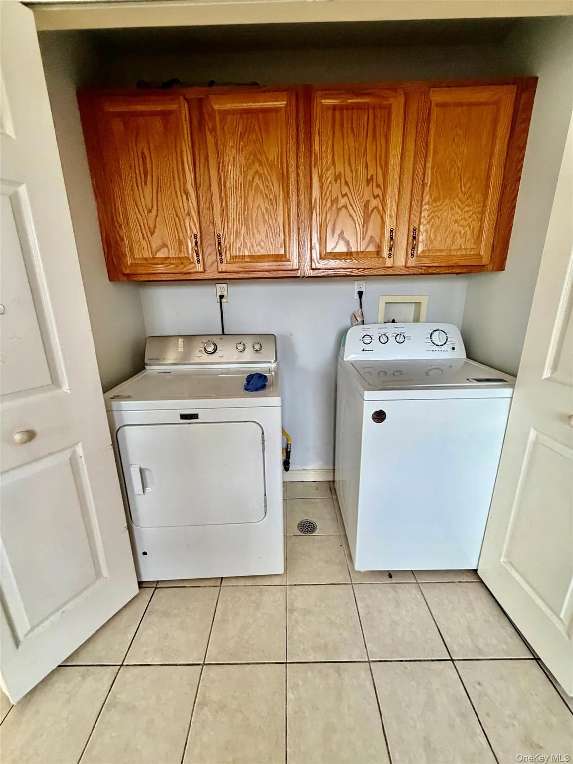 Washroom with cabinet space, independent washer and dryer, and light tile patterned floors Washroom with cabinet space, independent washer and dryer, and light tile patterned floors