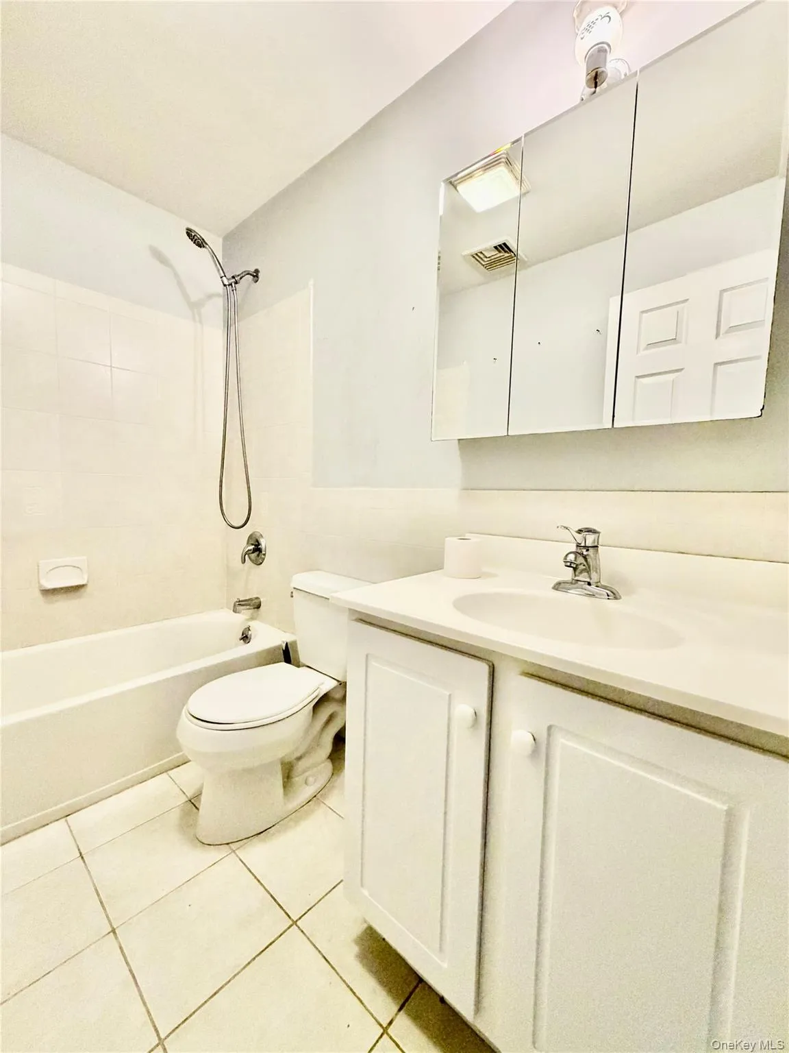Full bathroom with vanity, tub / shower combination, and light tile patterned floors Full bathroom with vanity, tub / shower combination, and light tile patterned floors