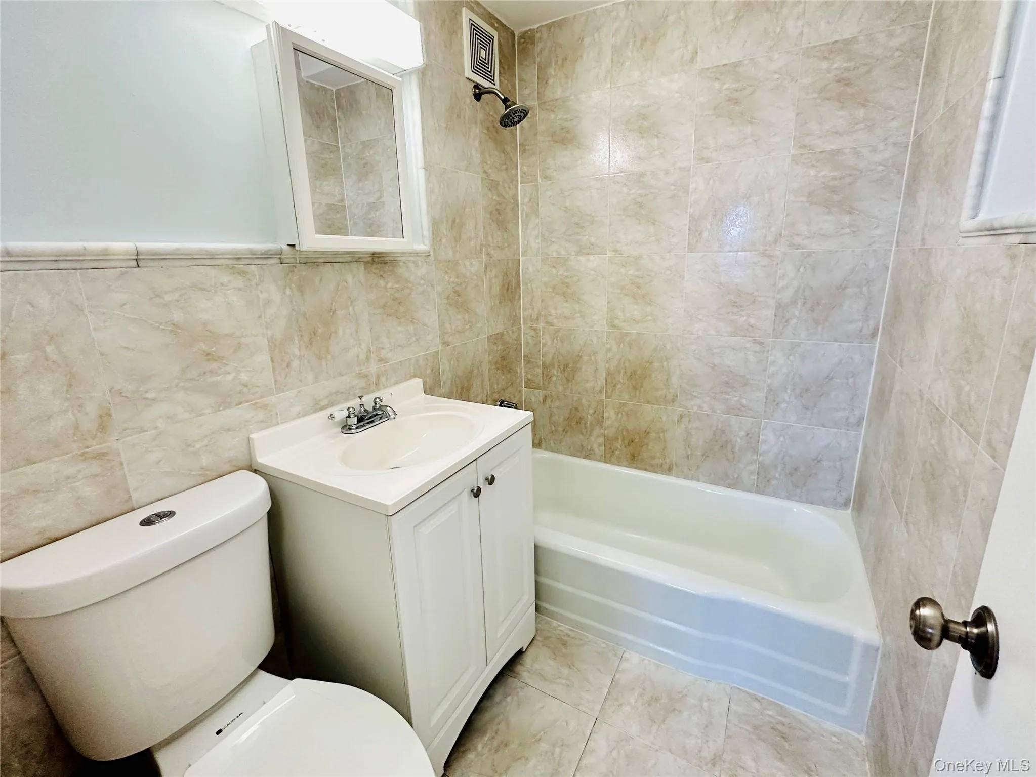 Full bathroom featuring vanity, tile walls, and shower / bath combination Full bathroom featuring vanity, tile walls, and shower / bath combination