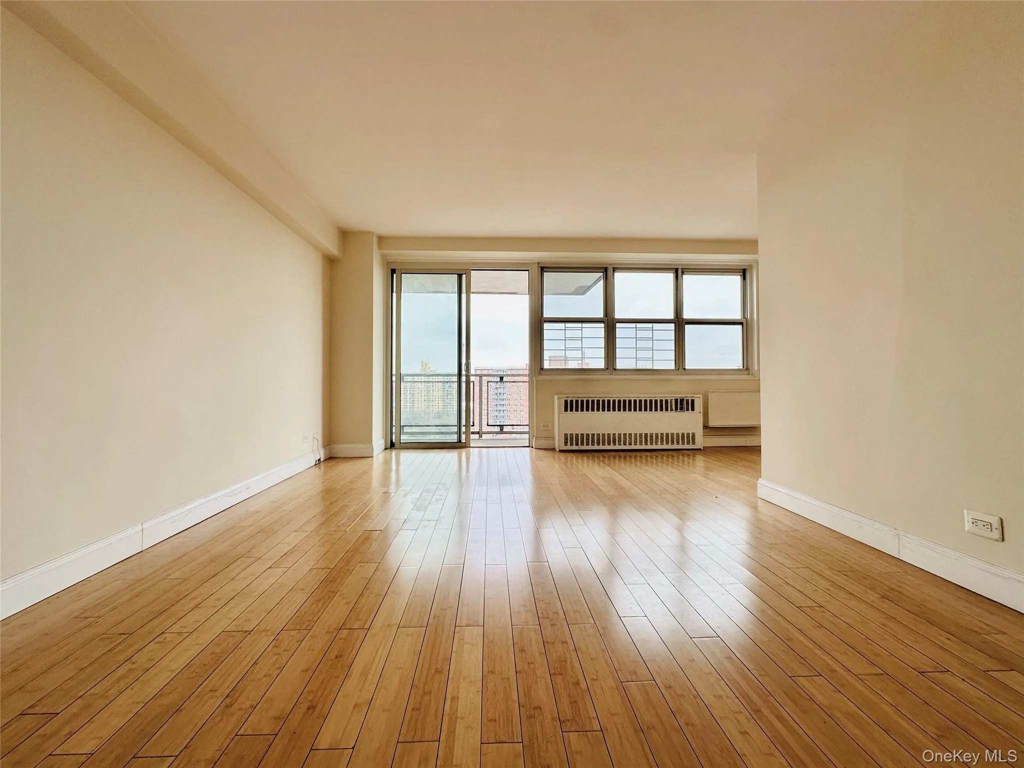 Unfurnished room with radiator heating unit, plenty of natural light, light wood-style flooring, and beam ceiling Unfurnished room with radiator heating unit, plenty of natural light, light wood-style flooring, and beam ceiling