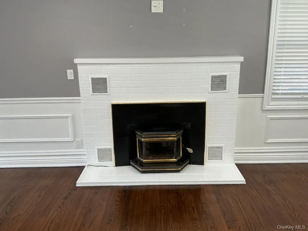 Detailed view of a wood stove, a decorative wall, wainscoting, and wood finished floors Detailed view of a wood stove, a decorative wall, wainscoting, and wood finished floors