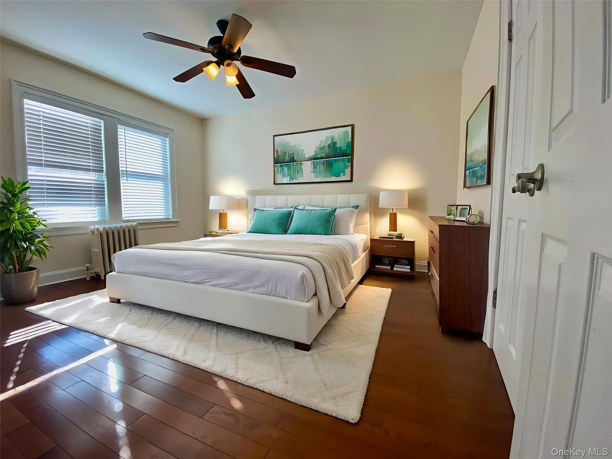Bedroom featuring radiator heating unit, hardwood / wood-style floors, and a ceiling fan Bedroom featuring radiator heating unit, hardwood / wood-style floors, and a ceiling fan