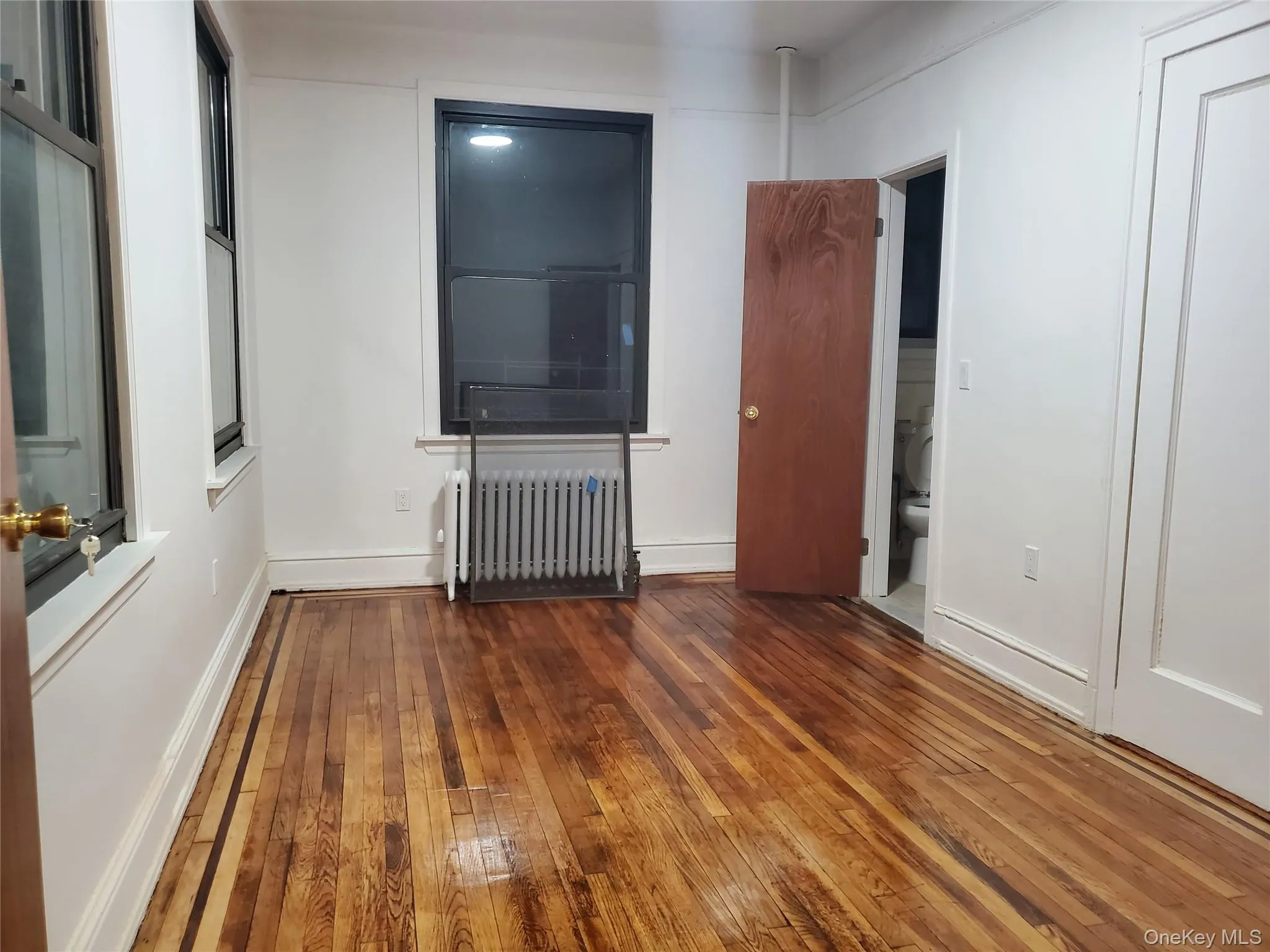 Unfurnished bedroom featuring radiator and wood-type flooring Unfurnished bedroom featuring radiator and wood-type flooring